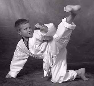 A young boy demonstrating a high kick from a floor position